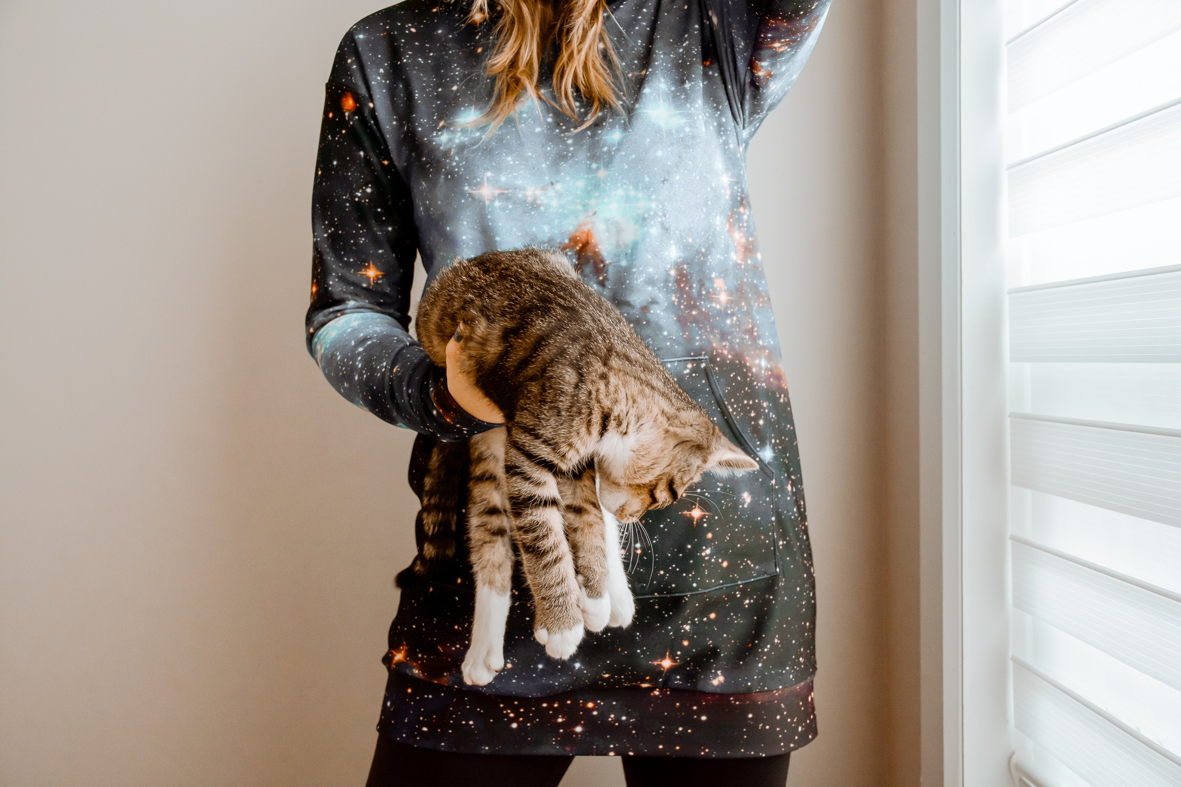 files/woman-wearing-hoodie-holds-cat-in-one-hand.jpg